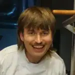 Koch in Pilzmanufaktur Freiburg, lächelnd in Kochjacke, bei Pilzverarbeitung.