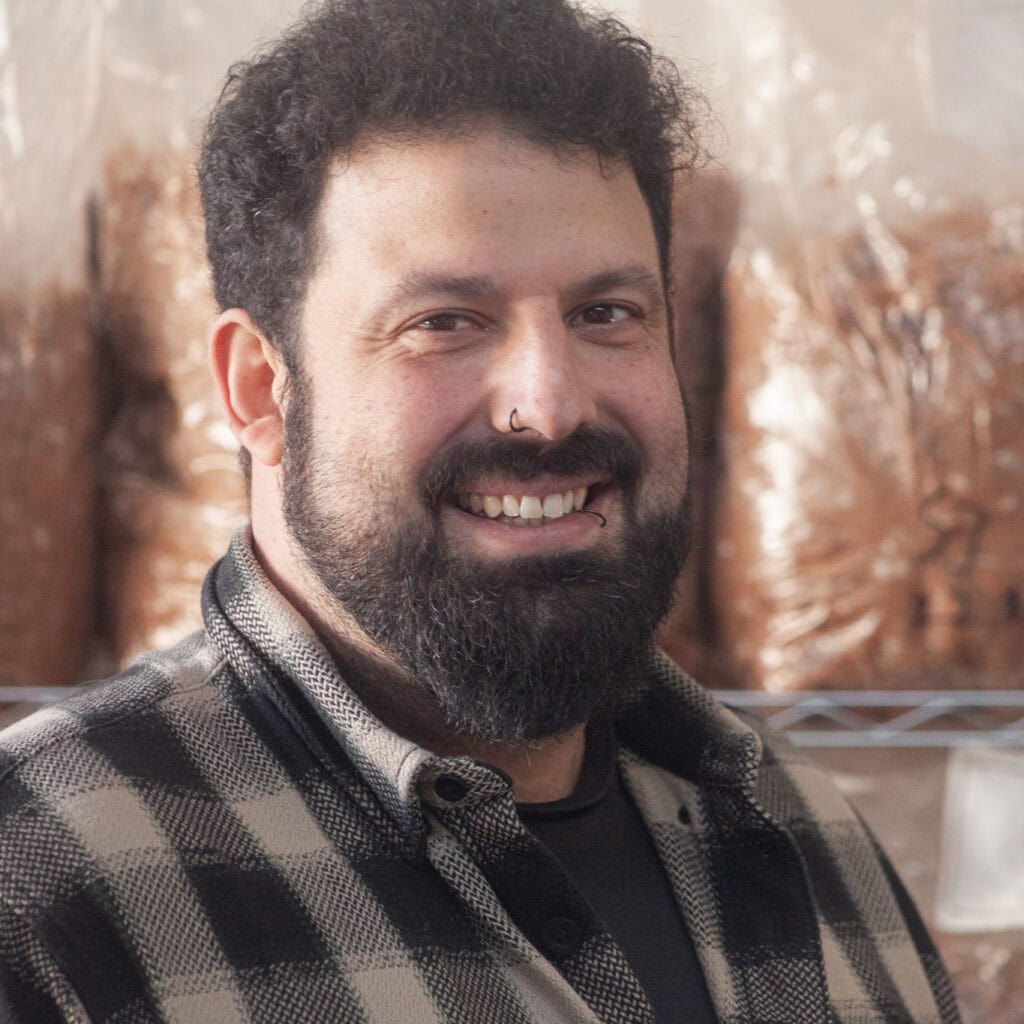 Mitarbeiter in der Pilzmanufaktur Freiburg, der frische, biologisch angebaute Pilze präsentiert.