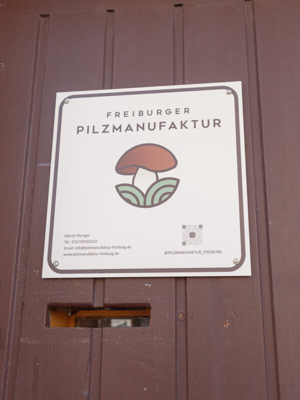 Pilzmanufaktur Freiburg Türschild, Logo und Name auf Holz.